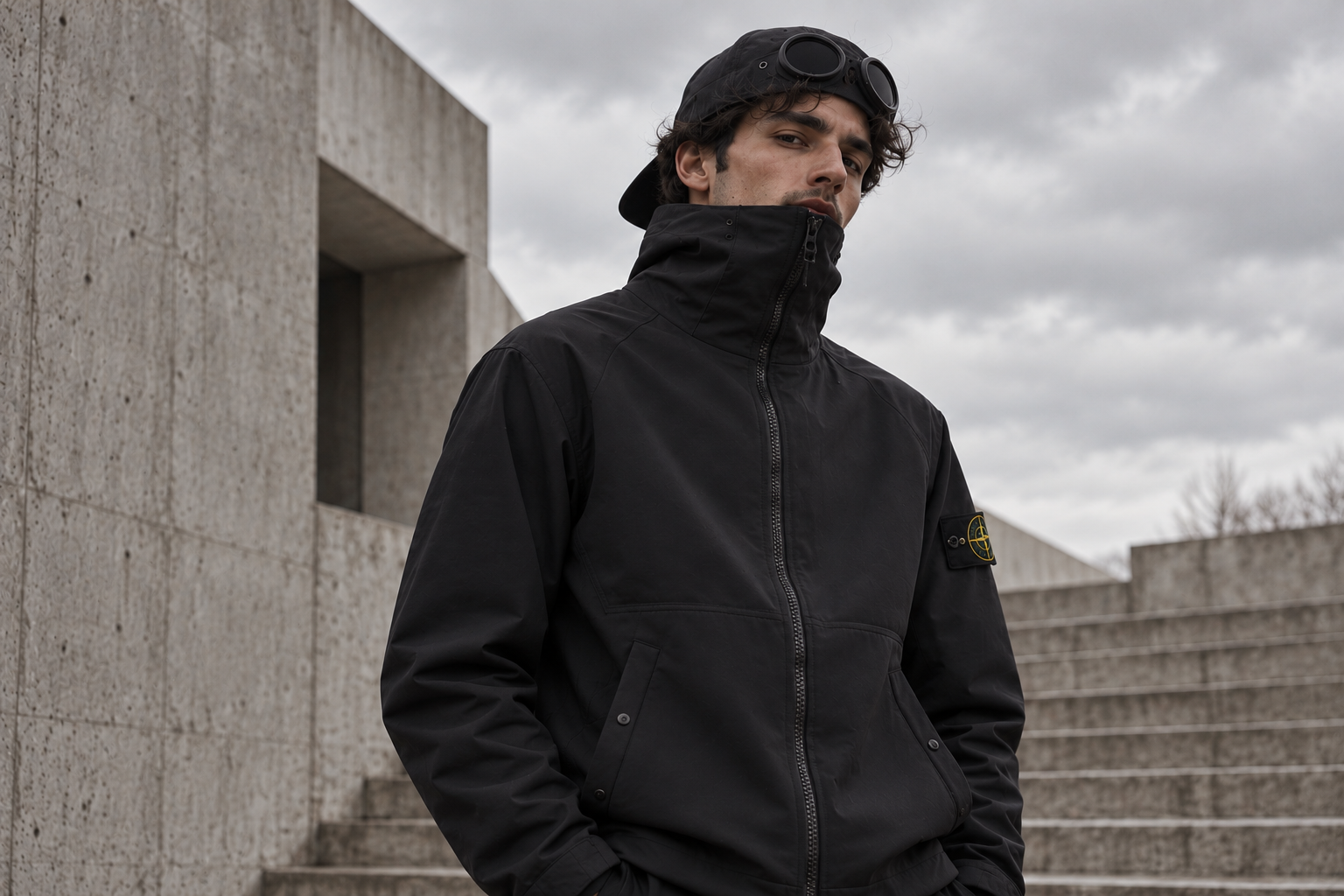 Silhouette en veste technique noire dans une architecture de béton
